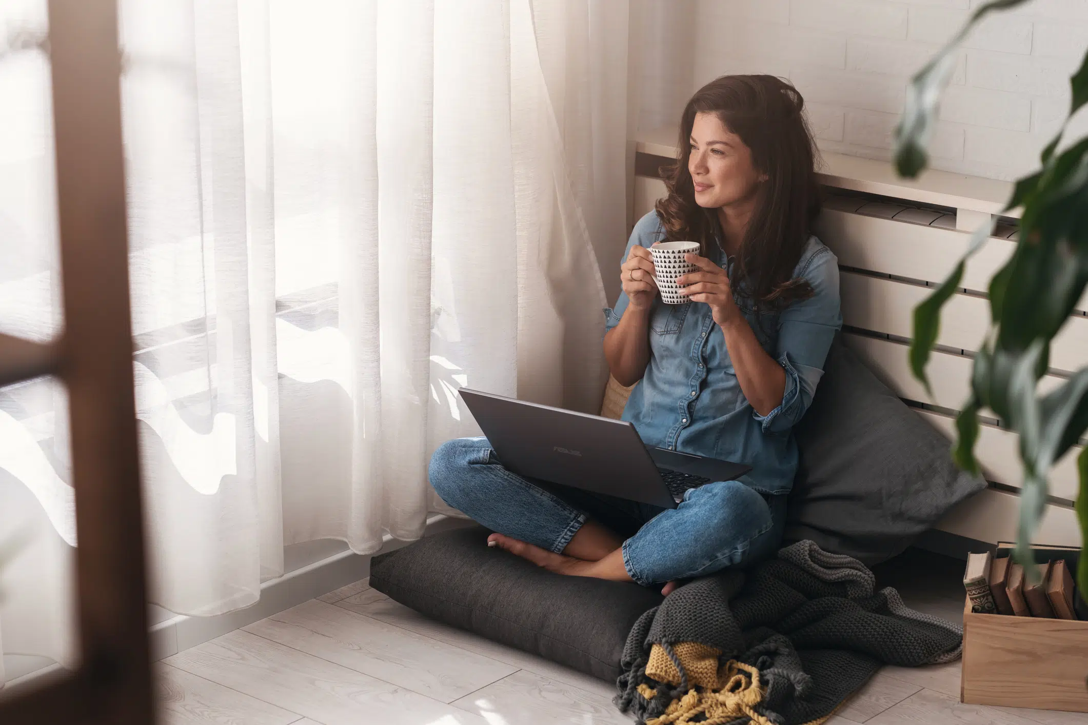 Happy young freelance business woman sitting on the floor at home working on a laptop computer